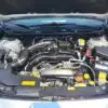 The hood of the 2018 Subaru Impreza Sport w/ Tech pkg is open, showcasing a well-organized engine bay with clean components like wires, caps, and a car battery in black, silver, and yellow. The tech package perfectly complements its sporty vibe.