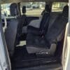 Inside the 2017 Dodge Grand Caravan SE, two black fabric seats are folded, revealing the spacious floor and providing a view of the neighborhood through the open door.