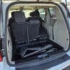 Rear view of a 2017 Dodge Grand Caravan SE with seats folded and mats on the cargo space, set against a snowy backdrop with other vehicles visible.