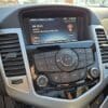 Car dashboard showing the radio and climate control panel, tuned to FM 104.5. The display also shows the temperature as 10°C and the time as 11:59 PM. Surrounding air vents and part of the steering wheel are visible.