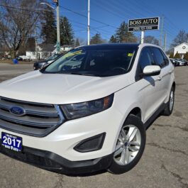 A white 2017 Ford Edge parked in a lot near a dealership sign that reads Boss Auto. The car is clean and the sky is clear, indicating a sunny day.